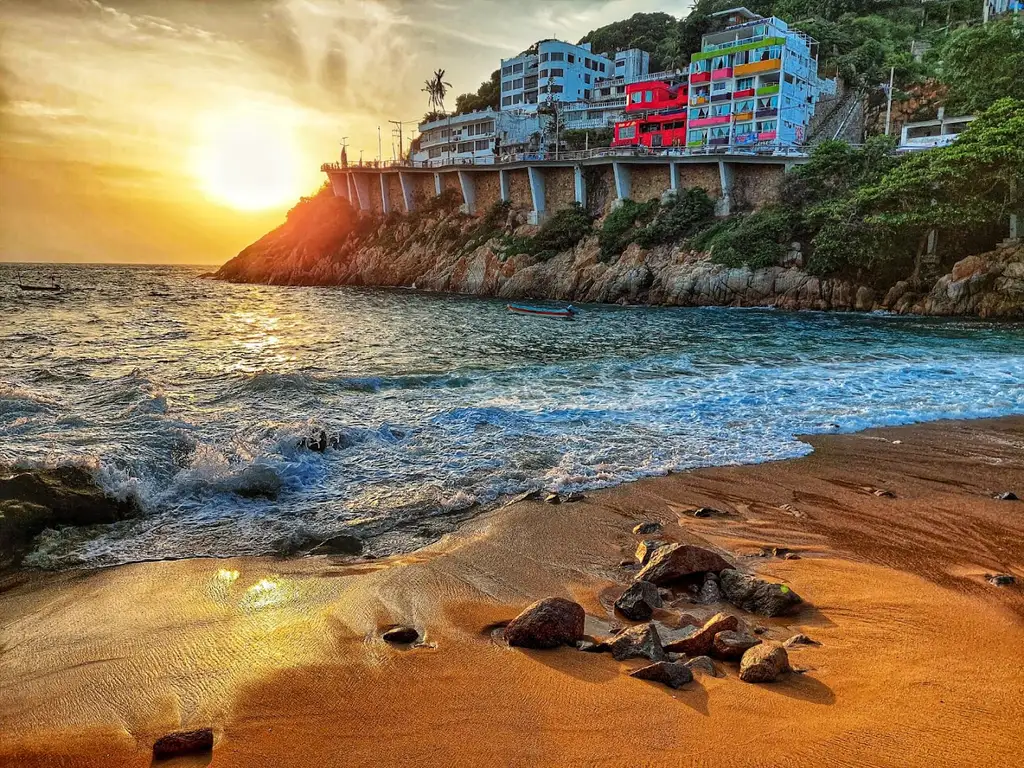 Atardecer sobre la playa de Acapulco, con el edificio de colores del Hotel Sinfonía sobre el acantilado