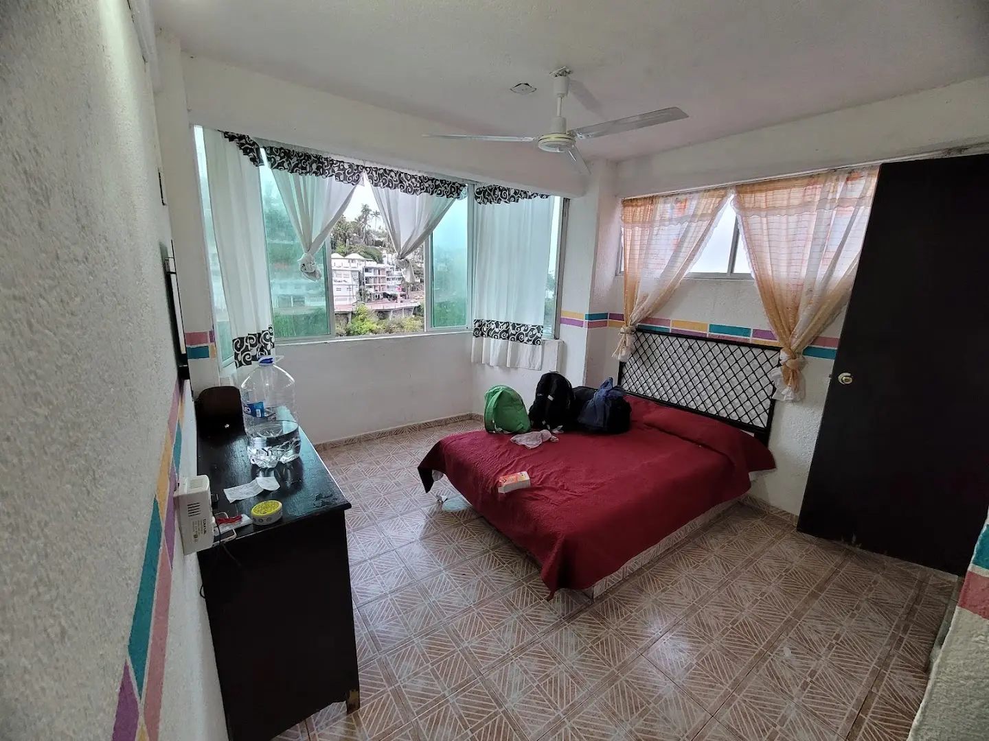 Habitación con cama matrimonial, ventilador de techo y ventana con vista al exterior